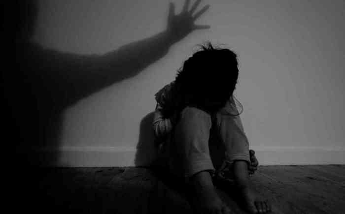 A child sitting in the dark with shadows lurking on her